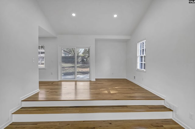 empty room featuring visible vents, high vaulted ceiling, wood finished floors, recessed lighting, and baseboards