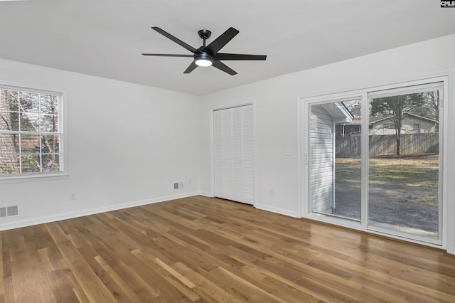 spare room featuring visible vents, baseboards, wood finished floors, and a ceiling fan