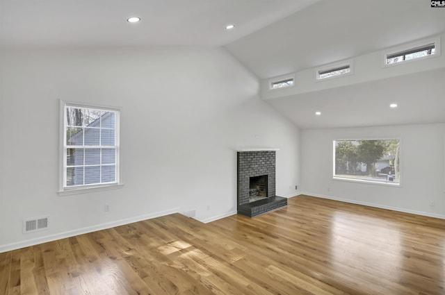 unfurnished living room featuring vaulted ceiling, a healthy amount of sunlight, visible vents, and light wood finished floors