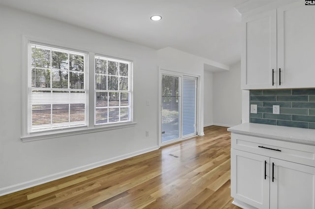 unfurnished living room with recessed lighting, baseboards, and light wood-type flooring