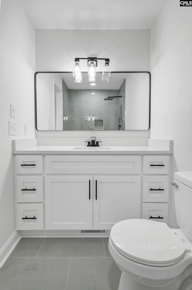 full bathroom with tiled shower, toilet, vanity, and tile patterned flooring