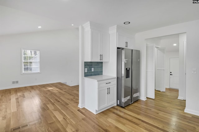 kitchen with light countertops, stainless steel fridge with ice dispenser, visible vents, and backsplash