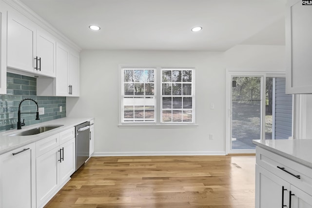 kitchen with a sink, tasteful backsplash, stainless steel dishwasher, and light countertops