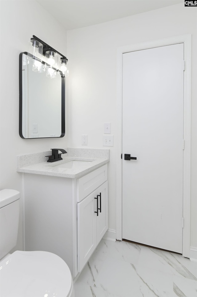 bathroom with vanity, toilet, baseboards, and marble finish floor