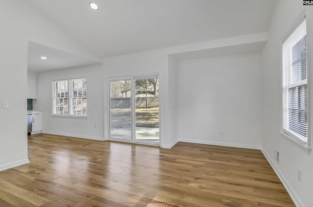 unfurnished living room featuring visible vents, baseboards, lofted ceiling, recessed lighting, and wood finished floors