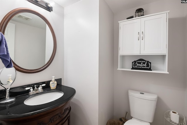 half bathroom featuring vanity, toilet, and visible vents