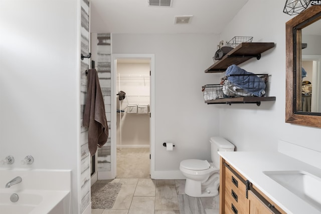 bathroom featuring visible vents, a walk in closet, toilet, a garden tub, and vanity