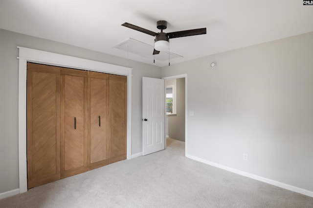 unfurnished bedroom with a ceiling fan, a closet, baseboards, light colored carpet, and attic access