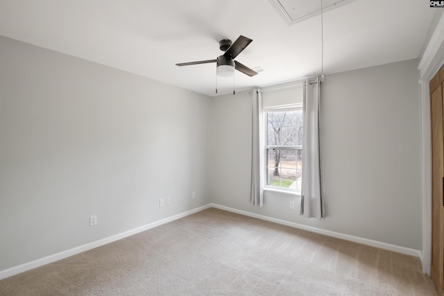 spare room featuring light colored carpet, attic access, baseboards, and a ceiling fan