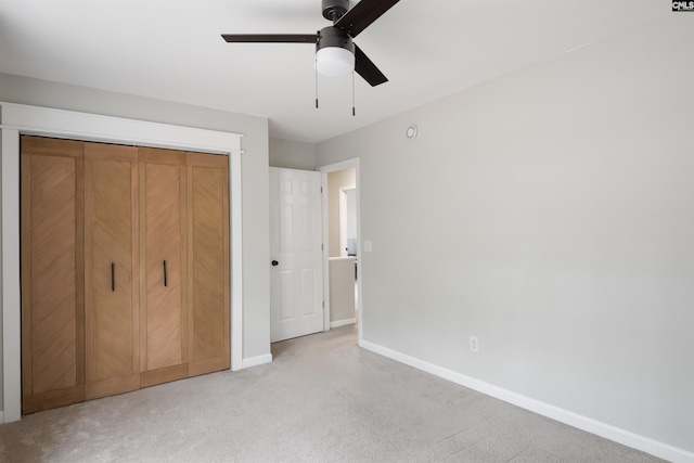 unfurnished bedroom featuring light carpet, ceiling fan, a closet, and baseboards