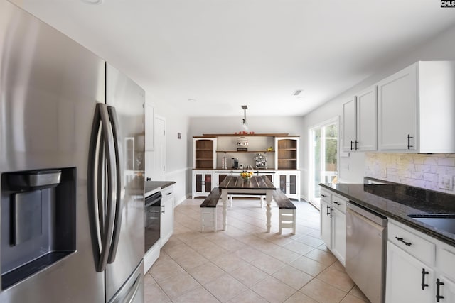 kitchen featuring light tile patterned flooring, backsplash, appliances with stainless steel finishes, and white cabinets