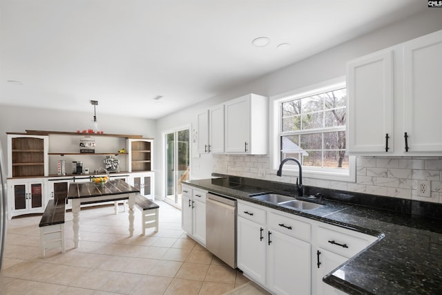 kitchen featuring light tile patterned floors, a sink, white cabinets, stainless steel dishwasher, and tasteful backsplash