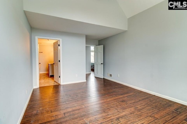 unfurnished bedroom featuring visible vents, lofted ceiling, baseboards, and wood-type flooring