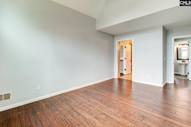 spare room featuring hardwood / wood-style floors, lofted ceiling, baseboards, and visible vents