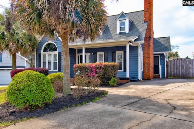 view of front of house featuring a shingled roof, fence, driveway, and a chimney