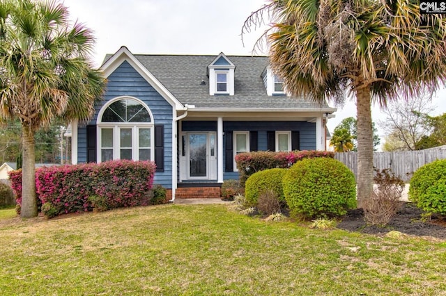 view of front of house with a shingled roof, a front lawn, and fence