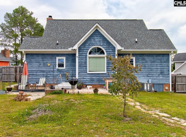 back of house featuring a yard, a patio, a chimney, and fence