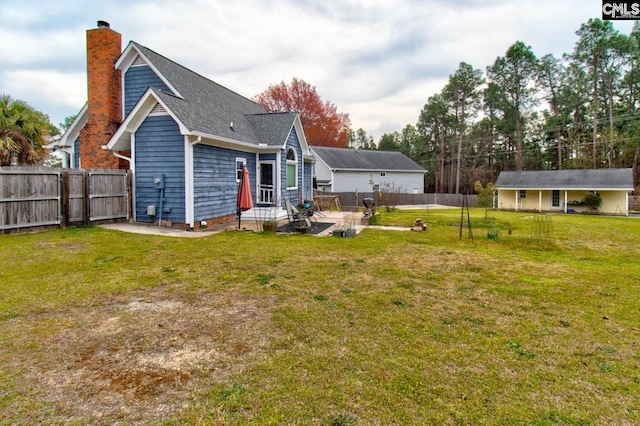 rear view of house with a yard, a patio area, a fenced backyard, and a chimney