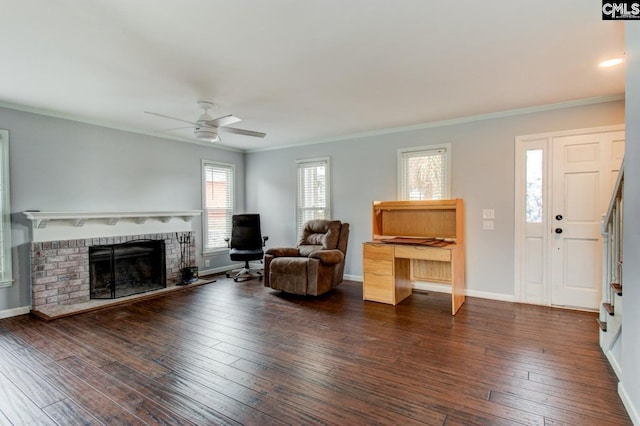 living area featuring hardwood / wood-style flooring, a brick fireplace, baseboards, and ornamental molding