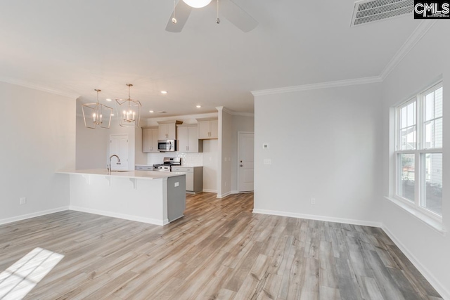 kitchen featuring visible vents, baseboards, a kitchen bar, appliances with stainless steel finishes, and a peninsula