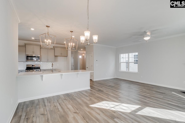 kitchen featuring crown molding, a breakfast bar, light countertops, appliances with stainless steel finishes, and a sink