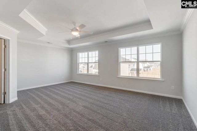 empty room with a ceiling fan, baseboards, a tray ceiling, crown molding, and dark colored carpet