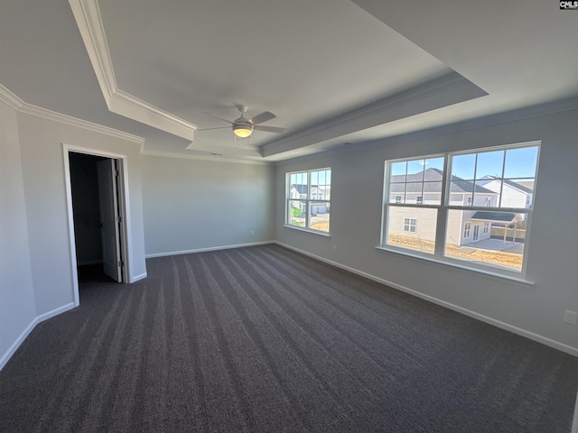 spare room featuring ceiling fan, baseboards, a tray ceiling, ornamental molding, and dark colored carpet