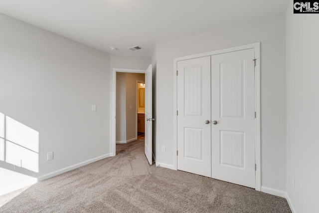 unfurnished bedroom featuring carpet, visible vents, a closet, and baseboards