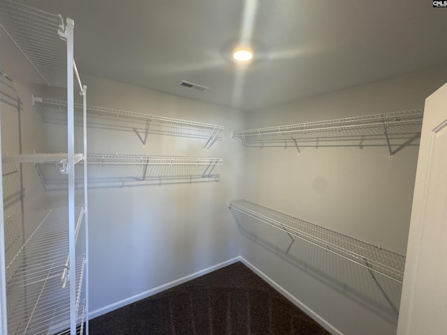 walk in closet featuring visible vents and dark colored carpet