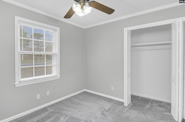 unfurnished bedroom with a closet, carpet flooring, crown molding, baseboards, and ceiling fan