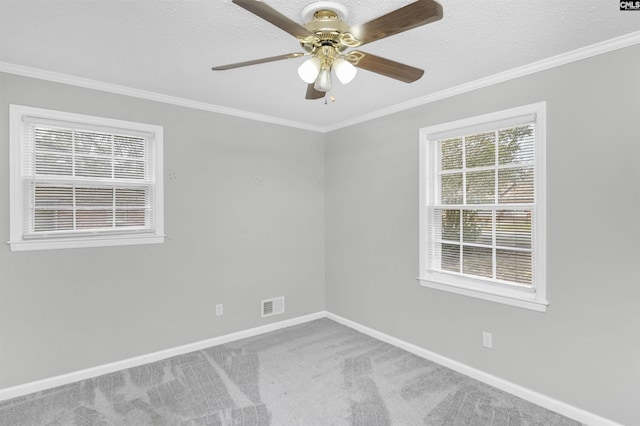 empty room with visible vents, ornamental molding, carpet flooring, baseboards, and ceiling fan