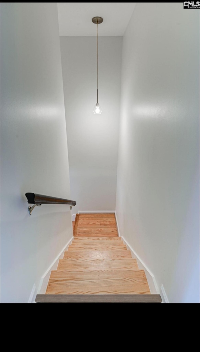 staircase featuring baseboards and wood finished floors