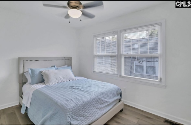 bedroom featuring visible vents, baseboards, wood finished floors, and a ceiling fan