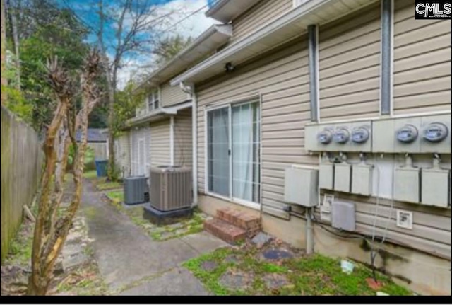 view of property exterior with central AC unit and fence