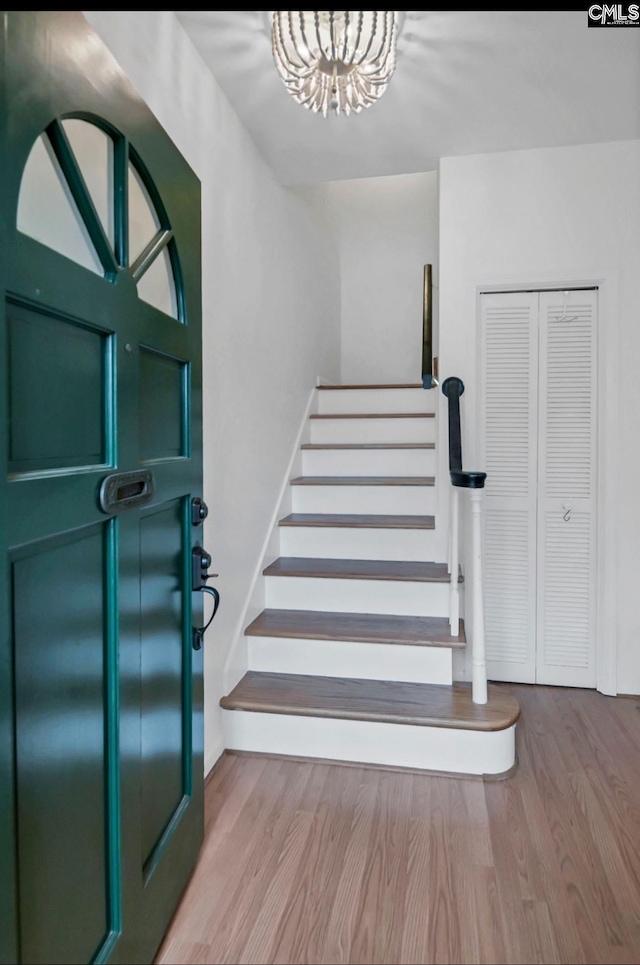 stairway with a notable chandelier, baseboards, and wood finished floors