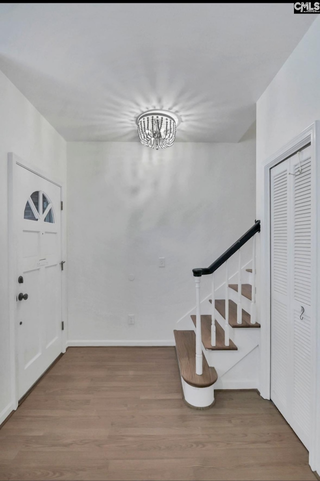 entryway with baseboards, wood finished floors, and stairs