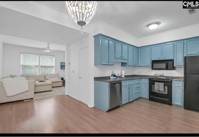 kitchen featuring black appliances, blue cabinetry, dark countertops, open floor plan, and light wood finished floors