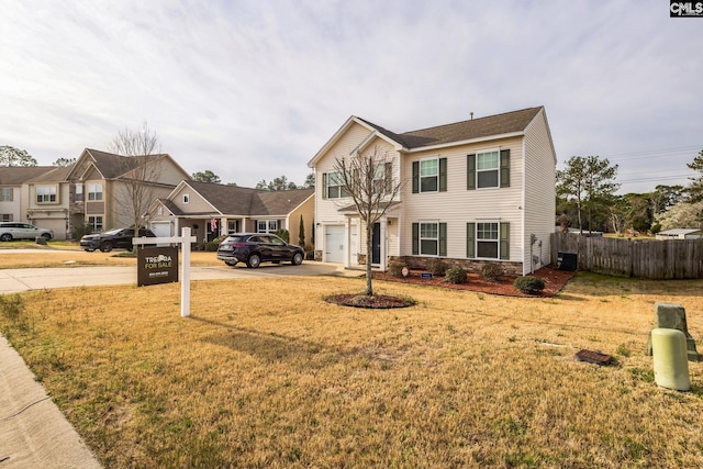 view of front of home featuring a front yard, fence, concrete driveway, a garage, and a residential view