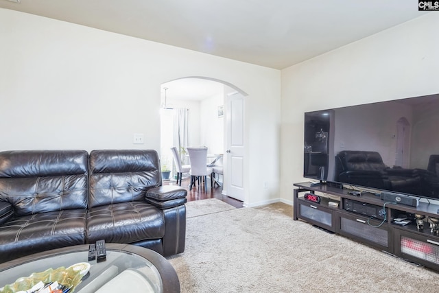 carpeted living room with baseboards and arched walkways