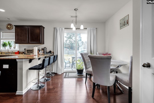 dining room featuring a notable chandelier, a healthy amount of sunlight, dark wood finished floors, and a toaster