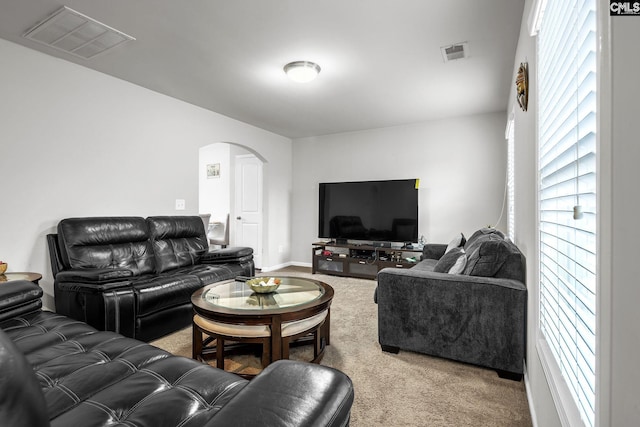 carpeted living area with arched walkways and visible vents