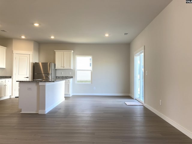 kitchen with dark wood-type flooring, an island with sink, freestanding refrigerator, recessed lighting, and white cabinets