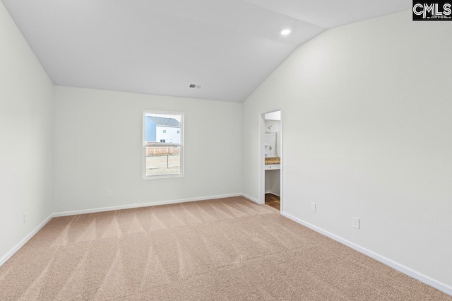 spare room featuring lofted ceiling, baseboards, visible vents, and light carpet