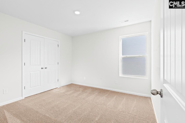 unfurnished bedroom with visible vents, baseboards, a closet, and carpet flooring