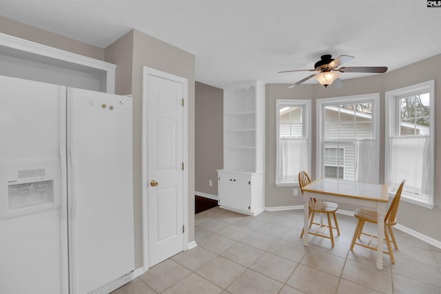 dining space with light tile patterned floors, a textured ceiling, baseboards, and ceiling fan