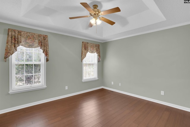 unfurnished room featuring a tray ceiling, a healthy amount of sunlight, and dark wood finished floors