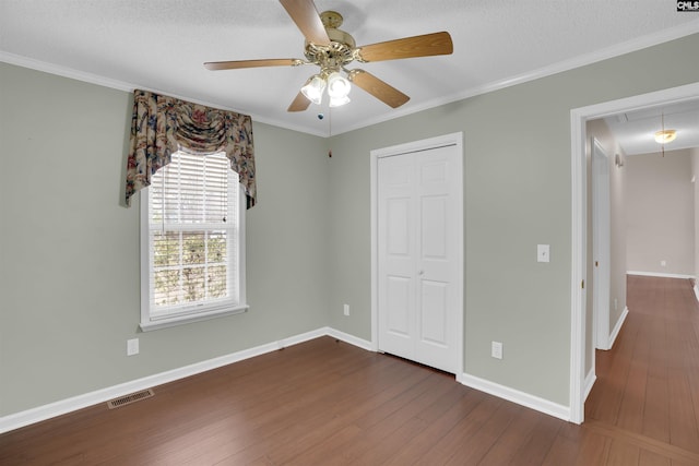 unfurnished bedroom featuring dark wood-style floors, visible vents, attic access, and baseboards