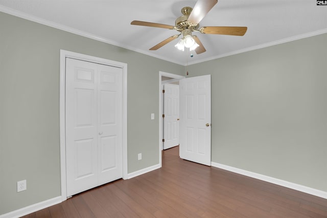 unfurnished bedroom with baseboards, dark wood-style flooring, ceiling fan, a closet, and crown molding