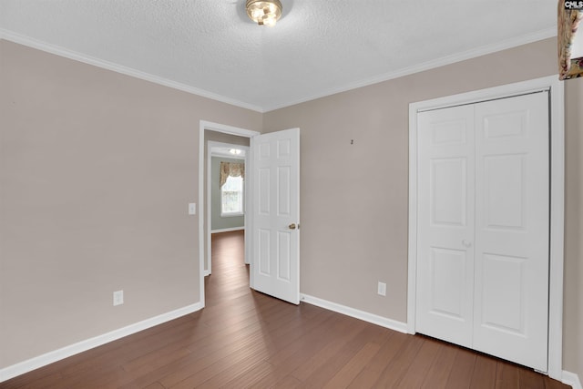 unfurnished bedroom featuring a textured ceiling, dark wood-type flooring, and baseboards