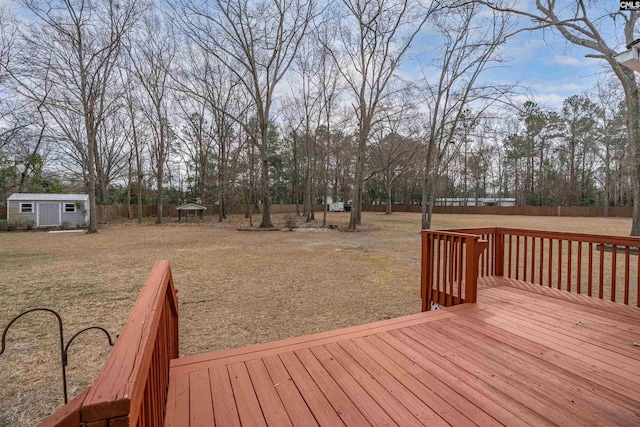 wooden terrace featuring a lawn, an outdoor structure, a storage shed, and fence